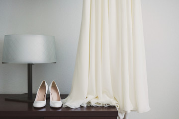 bride's shoes and white wedding dress during preparation in the morning