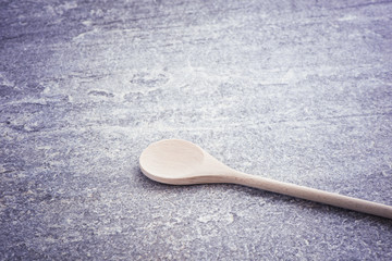 Wooden spoon on stone table. Traditional cooking equipment. Wood kitchenware object used for food, serving or cooking.