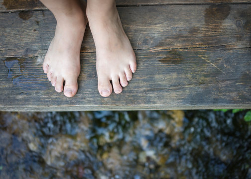 Kids feet standing on the wooden bridge in mountain creek