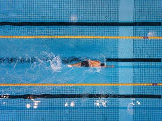 Young man swimming laps in a pool - Powered by Adobe