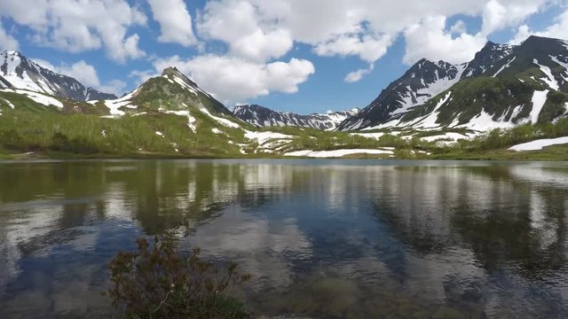 Summer landscape Kamchatka (time lapse): beautiful view of Mountain Range Vachkazhets, mountains and mountain lake and clouds drifting across sky on sunny day. Far East, Russia, Kamchatka Peninsula.