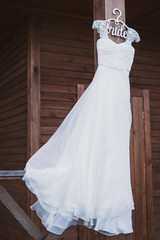 white wedding dress on custom hanger on wooden house