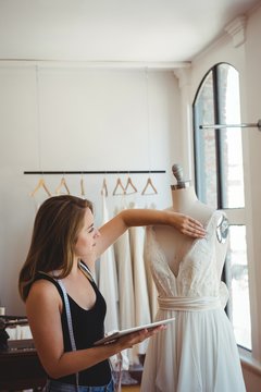 Female fashion designer adjusting the dress on mannequin