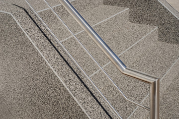 Fototapeta premium Moderner Handlauf und Edelstahlgeländer an einer Betontreppe mit Kieselbeschichtung - Contemporary handrail and stainless steel railing on a concrete staircase with gravel coating