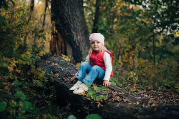 little girl in the red in the autumn forest among the trees