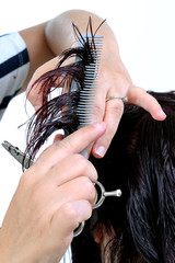 Hairdresser who performs a fashionable cut on the hair of a woman of Caucasian origin