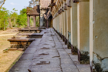 Ancient wall with frescoes and columns of ancient temple complex Angkor Wat in Siem Reap, Cambodia. Selective focus on the wall with the mural on the right