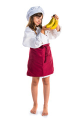 Little cute girl dressed like a chef holding bananas