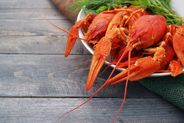 Boiled crayfish in a plate with parsley greens on a wooden background