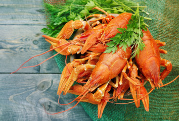 Boiled crawfishes in a round wooden plate on a wooden background, close up, top view