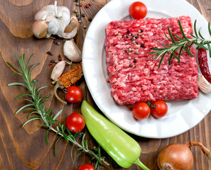 Raw fresh ground beef meat - minced meat on plate and spice (seasoning) with vegetable