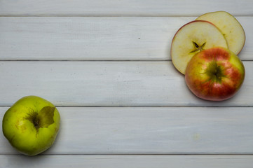 Whole and cut red and green ripe apples autumn harvest, from above on white wooden table