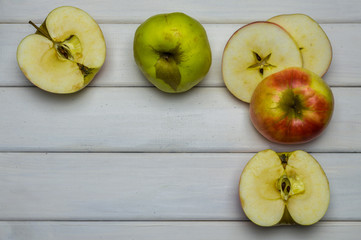 Whole and cut red and green ripe apples autumn harvest, from above on white wooden table