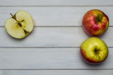Whole and cut red and green ripe apples autumn harvest, from above on white wooden table