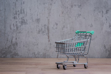 Empty shopping trolley on the wooden table over the concrete wall