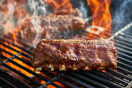 grilling baby back pork ribs over flaming grill