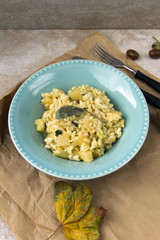 Risotto with patison and sage. Vegetarian dish, beige background and autumn leaves.