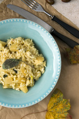 Risotto with patison and sage. Vegetarian dish, beige background and autumn leaves.