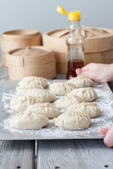 The process of making Asian dumplings. Female hands holding a tray of hand made dumplings 