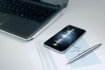 close up of smartphone, laptop and pen on table