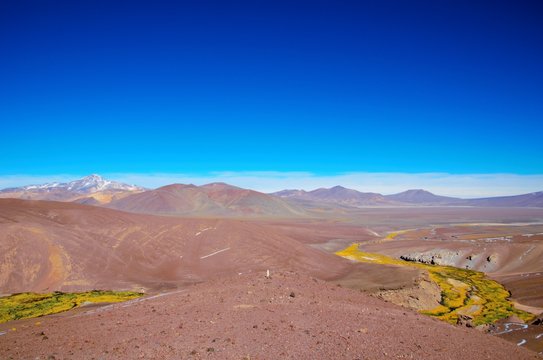 Panoramic view  over a green and yellow river between brown sandy hills on the way to Laguna Verde close to Copiapo in Chile, South America