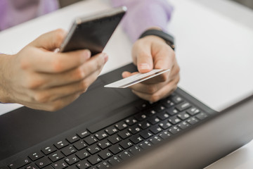 Hands holding plastic credit card and using laptop. 