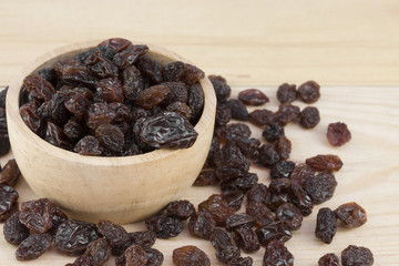 raisins in bowl on wooden table.