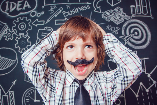 Little boy as businessman or teacher with mustache standing on dark background pattern. Wearing shirt and tie. He keeps holding his head. close-up