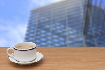 coffee on wooden table with buildings blur background