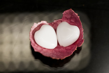 Litchi peel with heart shaped agate on black background