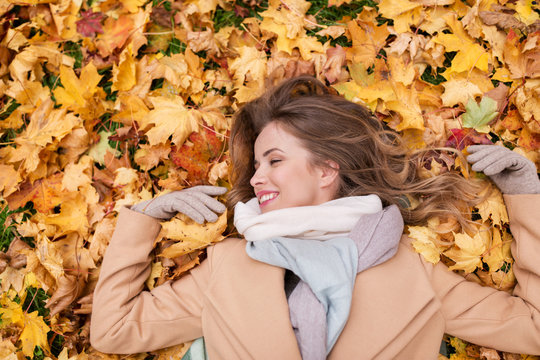 beautiful happy woman lying on autumn leaves