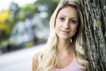 happy woman posing against a tree