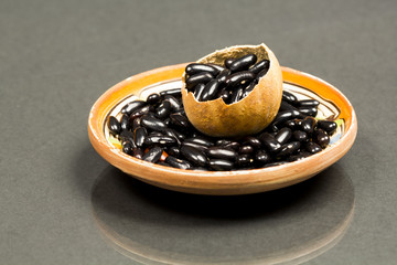 Black dried beans in a pumpkin shell and ceramics small plate with dark background