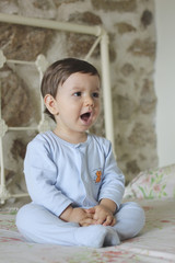 Fototapeta premium shouting baby sitting in bed with stone background