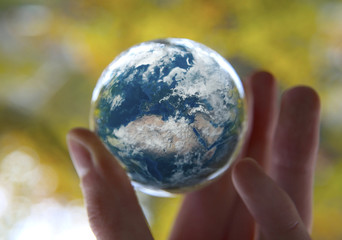 Man's hand holding the Earth with autumn Leaves background, Elements of this image furnished by NASA