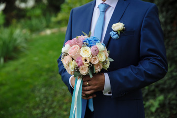 groom holding wedding bouquet in his hand
