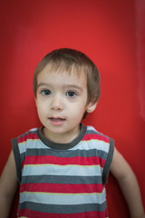 Cute little boy in front of red wall