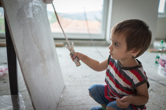 Little cute boy painting on a wall