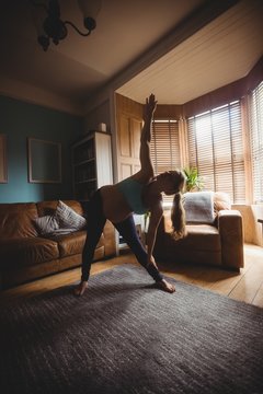 Pregnant woman performing stretching exercise in living room