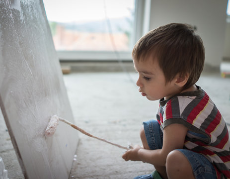 Little cute boy painting on a wall