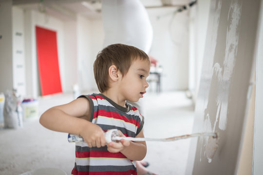 Little cute boy painting on a wall