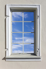 Wooden window in which the blue sky is reflected