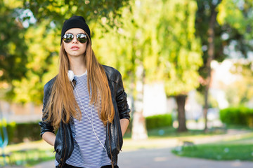 Cool teenage girl with sunglasses in urban outfit in park