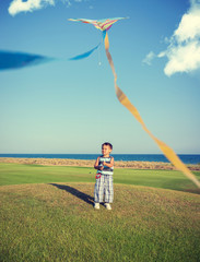 Little boy on summer vacation having fun and happy time flying k