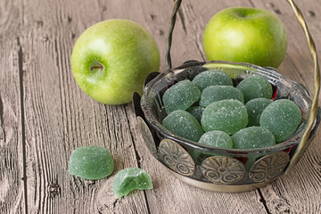  Fruit jelly in vase and apples.   Fruit jelly in old vase and two green apples on gray wooden table.