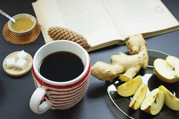 Cozy christmas reading with cup of coffee, honey, ginger root and apples.