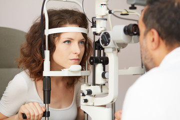 Fototapeta na wymiar Optometrist in exam room with woman in chair