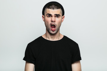 Obraz premium Male in a black t-shirt with an open mouth on a grey studio background