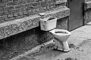 Old dirty toilet in the yard. Black and white