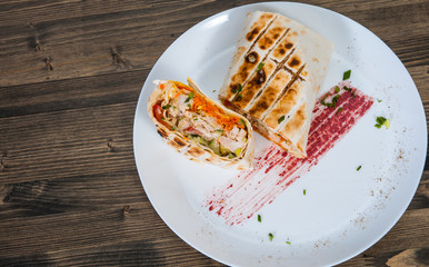 shawarma in thin pita bread with chicken and vegetables on a plate. top view